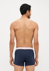 Námořnické modré boxerky s úzkým střihem, elastickým pasem s červenými a bílými pruhy a hladkým, elastickým materiálem.