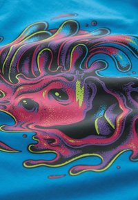 Impression graphique sur tissu bleu avec des couleurs vives : rose, violet, jaune, accompagnées de motifs tourbillonnants et de formes abstraites tout au long.