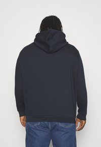 Marinblå huvtröja i mjukt tyg, med en avslappnad passform, långa ärmar och en känguruficka med ribbade manschetter och mudd.