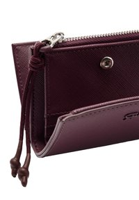 Portfel z bordo skóry o gładkiej fakturze, z zamkiem błyskawicznym i metalowym zatrzaskiem. Zawiera kieszeń z okrągłymi klamrami dla bezpiecznego przechowywania.