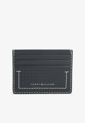 Smukły czarny portfel na karty Tommy Hilfiger z teksturowanym wzorem, białym przeszyciem i czterema przegródkami na karty.