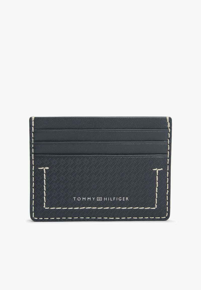 Porte-cartes noir et fin Tommy Hilfiger avec motif texturé, couture blanche et quatre emplacements pour cartes.