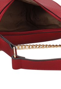 Borsa a tracolla in pelle rossa con tracolla a catena dorata e chiusura con cerniera. L'interno è in tessuto beige con logo del marchio.