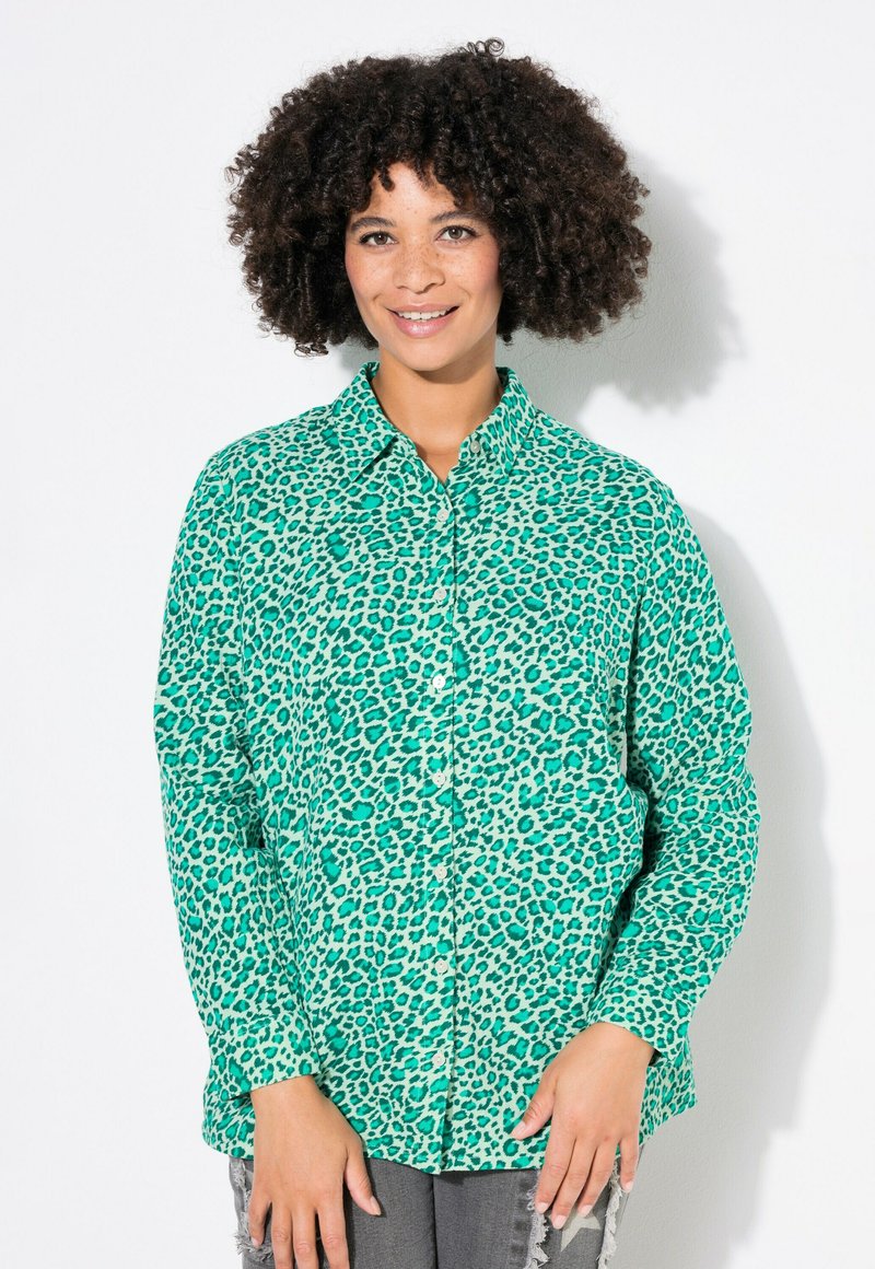 Groene luipaardprint knoopshirt met een klassieke kraag, lange mouwen en zachte stof. Gecombineerd met versleten grijze jeans.