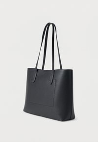 Čierna taška na rameno vyrobená z textúrovaného syntetického materiálu s dvoma dlhými rukoväťami, so štvorcovou nášivkou na prednej strane.