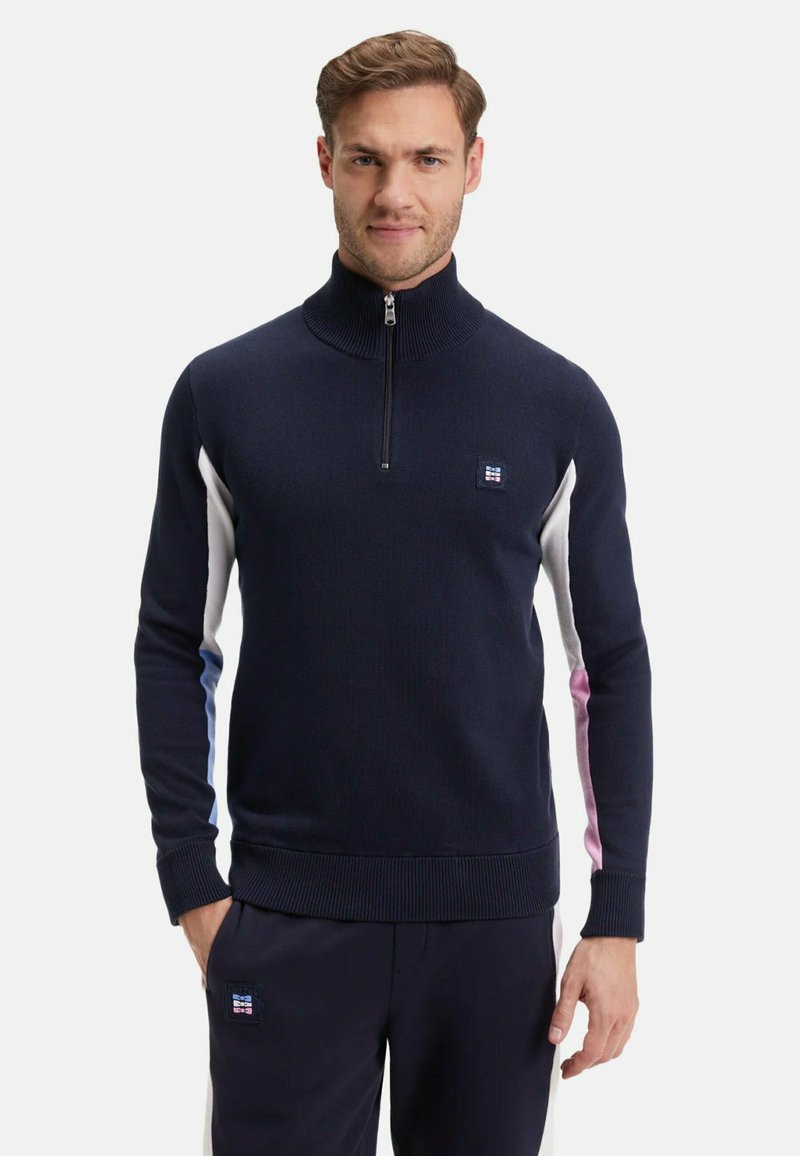 Pull en zip navy avec col montant ; comporte des panneaux sur les côtés en blanc, bleu clair et rose ; poignets et ourlet côtelés ; écusson avec logo sur la poitrine.