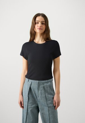 Svart T-skjorte med kort erme, rund hals og tettsittende design, kombinert med lyseblå plisserte bukser. Glatt tekstur og minimalt med detaljer.