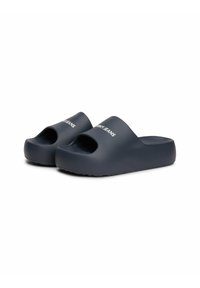Sandalias navy blue tipo slip-on con punta abierta, hechas de un material suave, con una suela gruesa y la marca "TOMMY JEANS" en texto blanco en la parte superior.