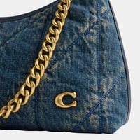 Coin de sac à main en denim bleu matelassé avec bandoulière chaîne dorée et détail du logo lettre "C" dorée sur fond blanc.
