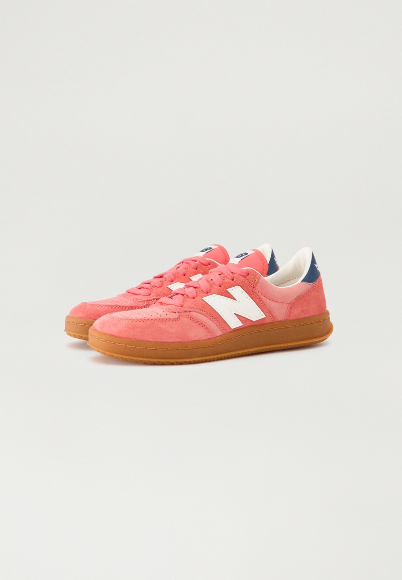 Zapatillas de ante rosa con logo blanco, suela de goma y acolchado en el collar. Presentan cordones y un acento en contraste en marino en el talón.