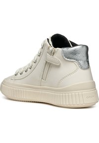 Sneaker alta bianca con un accento argento metallizzato nel tallone, suola in gomma testurizzata e una cerniera laterale accanto ai lacci.