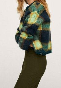 Przewymiarowany, przytulny sweter w zielono-niebiesko-żółtą kratę. Teksturowana tkanina z opuszczanymi ramionami i okrągłym dekoltem.