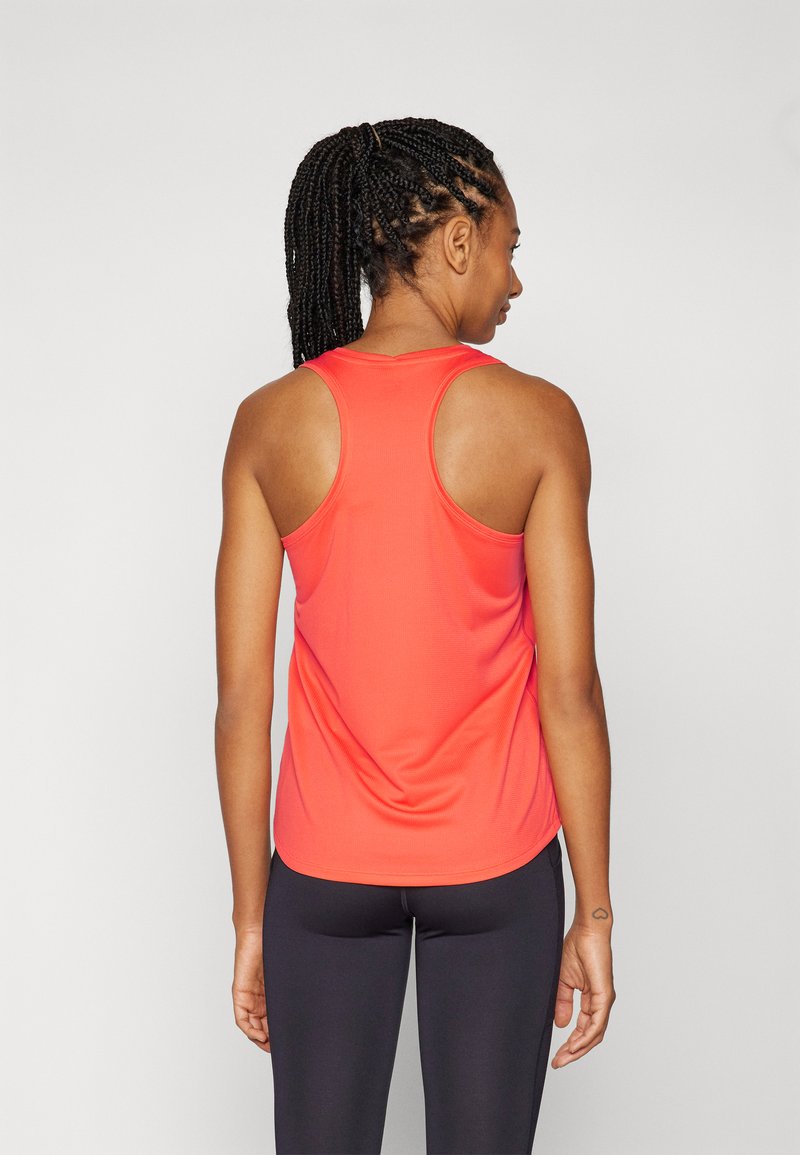 Débardeur de sport rouge avec un dos nageur, fabriqué en tissu respirant, porté avec des leggings noirs ajustés. Texture lisse, détails minimalistes.