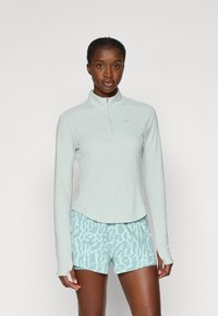 Světle mátově zelený dlouhý zip-up top s límečkem, doplněný o světle modré šortky s jemným vzorem zvířat.
