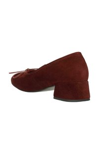 Scarpa bassa in suede bordeaux con punta rotonda, caratterizzata da un dettaglio a fiocco sul davanti. Superficie leggermente testurizzata con tacco largo.