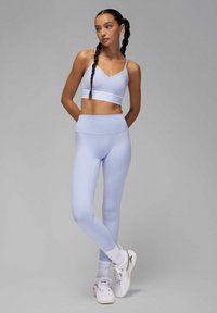 Sujetador deportivo azul claro y leggings a juego hechos de material elástico, con una cinturilla ancha y un logo sutil. Zapatillas completan el look.