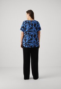 Blue patterned short-sleeve top with black abstract designs, paired with high-waisted black wide-leg trousers. Smooth texture, relaxed fit.
