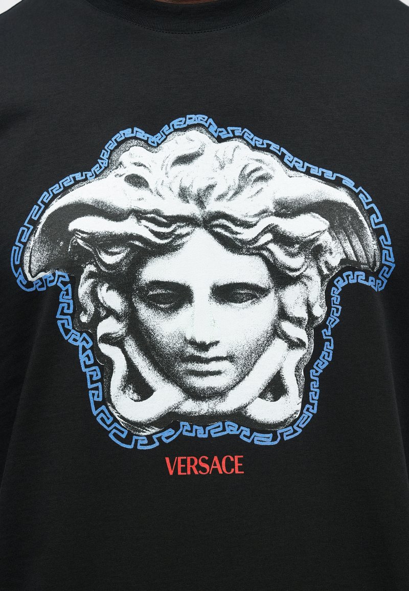 Black cotton t-shirt featuring a large white and blue graphic of Medusa's head, accented with a Greek key pattern and red "VERSACE" text.