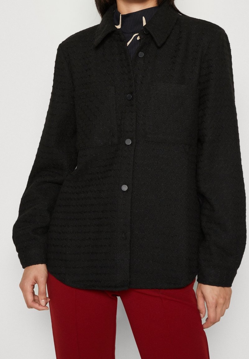 Zwarte shirtjack van een wolmix met een gestructureerd patroon, knoopsluiting aan de voorkant, puntige kraag en één borstzak. Lange mouwen en een relaxte pasvorm.