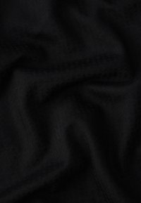 Texturovaná černá tkanina s jemným vzorem, měkkou texturou a mírným leskem, přirozeně splývá s jemnými záhyby a ohyby.