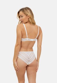 Ensemble de lingerie avec dentelle blanche comprenant un soutien-gorge à bretelles ajustables et une culotte haute assortie avec un motif triangulaire.