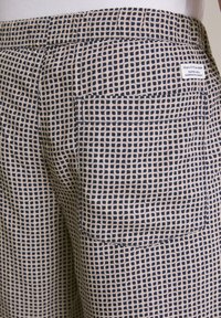 Blauwe en crèmekleurige geweven stof shorts met een achterzak, elastische tailleband en een gestructureerd geometrisch ontwerp. Kleine logotag zichtbaar.