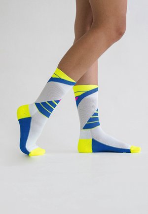 Bunte Knöchelsocken mit einer Mischung aus Weiß, Blau und leuchtendem Gelb, die geometrische Muster und kontrastierende Akzente an den Bündchen und Spitzen aufweisen.