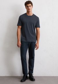 Donkergrijze katoenen T-shirt met ronde hals, gecombineerd met donkerblauwe slim-fit broek en zwarte veterschoenen. Minimalistisch ontwerp, geen patronen.