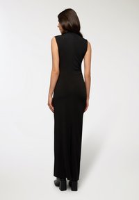 Abito maxi senza maniche nero con silhouette aderente e spacchi posteriori. Tessuto liscio, scollo alto e design semplice senza decorazioni.