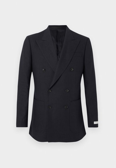 Μαύρο σακάκι διπλής σειράς με πέτα ανοιχτού τύπου, έξι κουμπιά, δύο μπροστινές τσέπες και μια μικρή ετικέτα στο κάτω μέρος του μανικιού.
