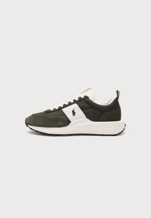 Basket vert olive et blanche à lacets sur le devant, semelle noire, semelle intercalaire blanche et logo de cheval noir sur le côté, présentée sur un fond uni clair.