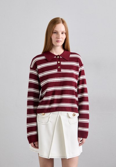 Polo de manga larga a rayas marrón con collar y tres botones. Combinado con una falda blanca que presenta dos bolsillos delanteros y detalles en dorado.