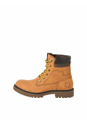 Kožené kotníkové boty v tan barvě se žlutými tkaničkami, hnědým polstrovaným límcem, texturovanou podrážkou a kulatým logem na vnější straně.