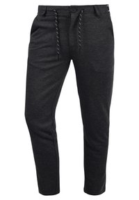 Pantalones jogger de color gris oscuro, fabricados en una tela suave con cintura elástica, cierre de cordón y bolsillos laterales. Diseño ajustado.