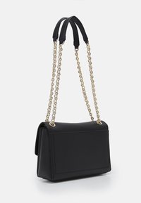 Černá kabelka z umělé kůže s obdélníkovým tvarem, zlatými řetízkovými popruhy a hladkou texturou. Má plochý přední panel a detaily švů.