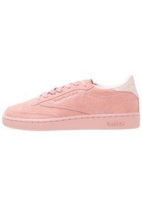 Baskets basses en daim rose avec doublure intérieure blanche, lacets et logo Reebok sur le côté et la semelle.