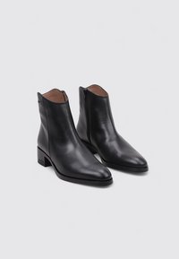 Botas de cuero negras hasta el tobillo con punta afilada, cremallera lateral y tacón bajo cuadrado. Textura suave y diseño minimalista.