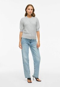 Lichtgrijze kortemouwige cardigan met een ronde hals, knoopsluiting en een zachte textuur, gecombineerd met lichtblauwe hooggesneden denim jeans.