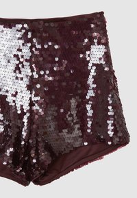 Shorts bordeaux à paillettes courtes avec des paillettes rondes iridescentes couvrant tout le tissu sur un fond gris clair.