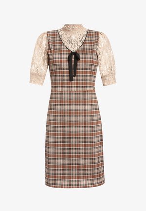 Woman wearing a knee-length brown plaid dress with black bow and beige lace half-sleeve top, paired with beige ankle-strap heels.