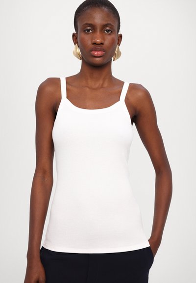 Hvit ribbet tanktop med smale stropper og rund hals. Stoffet ser mykt og tettsittende ut, som fremhever kroppens fasong.