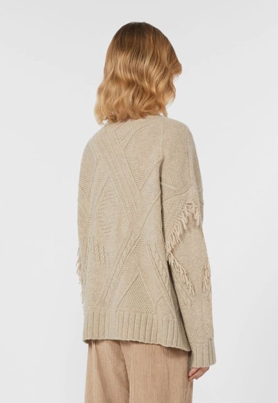 Maglione beige lavorato a maglia con motivi testurizzati, caratterizzato da dettagli in frange lungo le maniche. Vestibilità comoda con scollatura a girocollo.