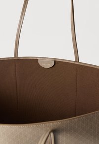 Τσάντα ώμου Calvin Klein σε χρώμα ταμπά με λείο συνθετικό εξωτερικό και υφήστερο καφέ εσωτερικό. Διαθέτει μακριές λωρίδες και λεπτομέρεια με το λογότυπο.