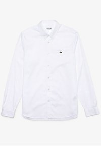 White long-sleeve button-up shirt, cotton material, classic collar, and a small green Lacoste logo on the chest. Simple and elegant design.