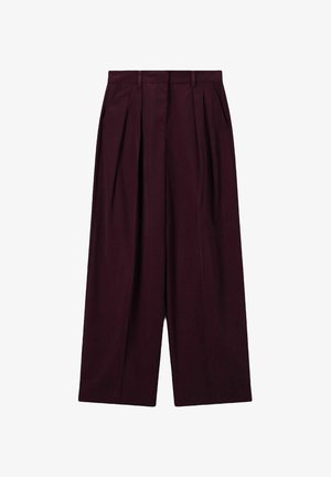 Pantalons larges, taille haute, de couleur violet foncé, avec plis avant, poches latérales, passants de ceinture et fermeture frontale dissimulée.