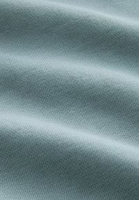 Tessuto di maglia blu chiaro con un fine motivo testurizzato e pieghe morbide che creano delicati ombre e luci.