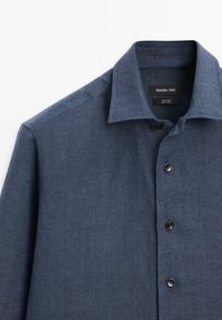 Herren-Langarm-Leinenhemd in Marineblau mit spitzem Kragen und schwarzen Knöpfen, mit dem Label Massimo Dutti.