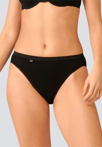 Slip in cotone nero con un delicato bordo in pizzo sulla cintura e sulle aperture delle gambe, caratterizzato da un piccolo etichetta sul lato.