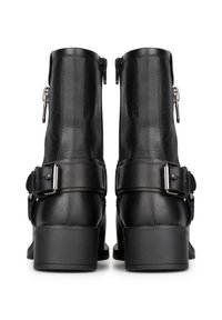 Botas negras de cuero hasta el tobillo con una textura suave, que presentan una cremallera lateral y una correa ancha con un detalle de hebilla. Los tacones de bloque completan el diseño.