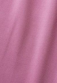 Gros plan d'un tissu rose lisse avec une texture tissée subtile et des plis doux et fluides.